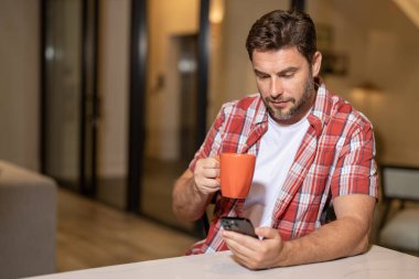 Geceleri akıllı telefonlu neşeli bir adamın portresi. Adam evde telefon kullanıyor. Çevrimiçi ödeme için telefonu kullanan Ortadoğulu olgun bir adam. Cep telefonu kullanan bir adam. Akıllı telefon ve mobil uygulama kullanan bir adam.