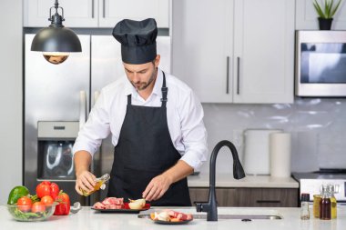 Modern mutfakta yemek pişiren adam. Adam evde ev işi yapıyor, mutfakta kahvaltı hazırlıyor. Yakışıklı adam mutfakta yemek pişiriyor. İspanyol adam mutfakta sağlıklı yemek pişiriyor.
