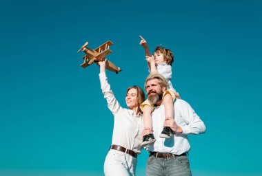 Aile eğlencesi, mutlu anne, baba ve oyuncak uçağı olan küçük çocuk. Sevgi dolu bir aile. Oyuncak uçakla oynayan ve geleceği hayal eden çocuk, rüya ve seyahat kavramı