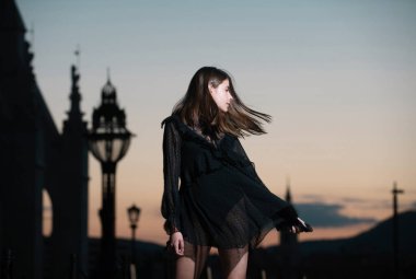 Şehrin arka planında şık giyinen zarif bir kadının sokak tarzı fotoğrafı. Avrupa şehrinin caddesinde yürüyen manken