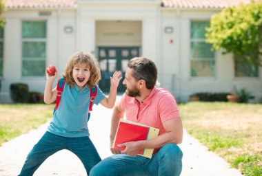 Öğretmenler günü. Baba oğul okul parkında yürüyorlar. Çocuğunu okula götüren ebeveyn