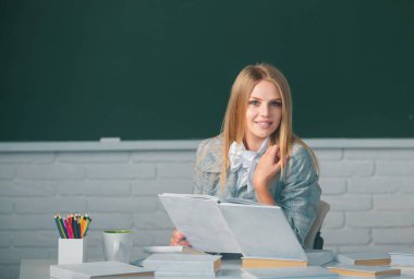 Genç kız üniversite öğrencisinin portresi, karatahta arka planlı sınıfta okuyor.