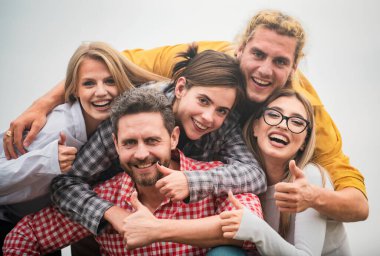 Farklı kültürlerden ve ırktan mutlu arkadaşlar başparmağıyla selfie çekiyorlar. Gençlik ve arkadaşlık kavramı. Bir grup arkadaş dışarıda kahkaha atıyorlar, iyi ve olumlu ruh hali.