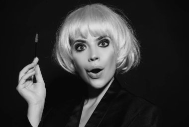 Güzellik salonunda fırçayla kaşlarını tarıyor. Uzun kirpikleri ve kalın kaşları olan komik bir kadın.