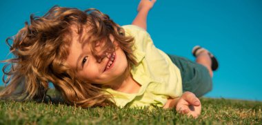 Yeşil çimlerde oynayan mutlu çocuk. Baharın bahçesinde komik bir çocuk. Çocuk günü konsepti