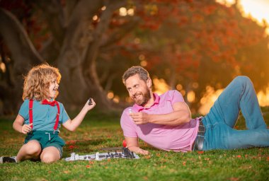 Baba oğluyla satranç oynar. Aile oyunu dışında. Akıllı çocuk, akıllı çocuklar.