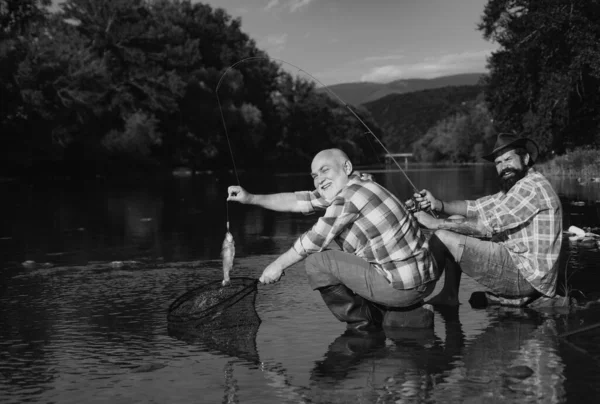两个男人朋友是在河里钓鱼的渔夫 老父子俩在河边钓鱼 文娱活动 — 图库照片