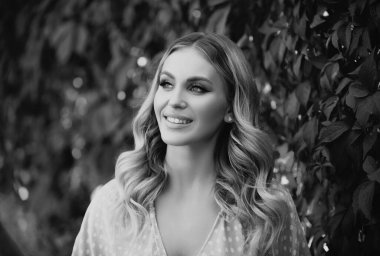 Portrait of a young woman, close up face of beautiful woman in park outdoor. Woman with romantic smile. Cheerful female model