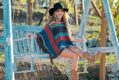 Yazın salıncakta sallanan boho tarzındaki şehvetli hippi kadın, bahar parkında şapka takan genç seksi kız. Özgürlüğün tadını çıkaran ve tasasız hisseden genç bir kadın.