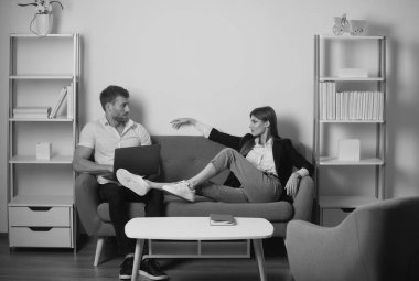 İş çifti ofiste dinleniyor. Genç iş çifti ofiste rahat rahat giyinip bilgisayar laptopuyla çalışıyorlar.