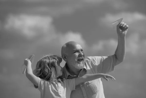 孙子孙女和祖父与纸飞机在蓝天和云彩之上 外公外公外孙一代 — 图库照片
