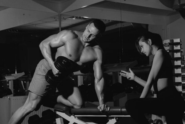 Женщина-тренер с мускулистым мужчиной занимается функциональной тренировкой, поднимая гантели. Сила, сила и здоровый образ жизни, спорт