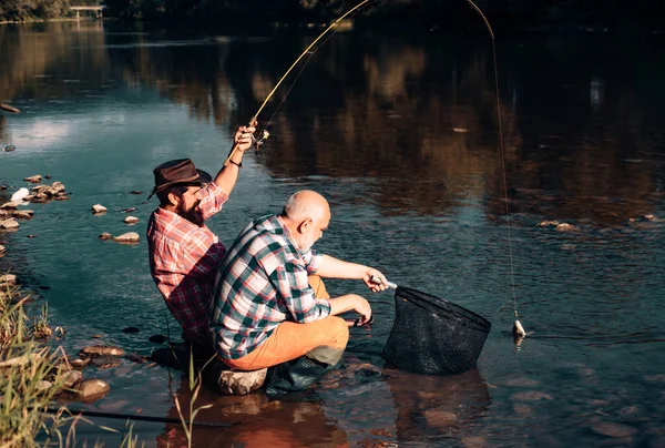 明るい老人釣りの肖像画 祖父と息子の漁師 川や湖でスピニングのための若い男と老人釣り マス釣り — ストック写真
