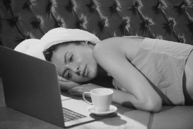 Sabah uyandıktan sonra yatak odasında dizüstü bilgisayarı ve kahvesi olan rahat genç ve seksi kadın modeller. Çekici seksi kız oturma odasında dinleniyor.