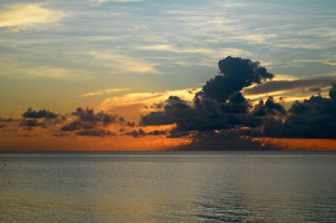 Tropikal deniz okyanusunda gün batımı ve gündoğumu bulutları. Seyahat tatili afişi. Manzara gökyüzü ve yansıma ışınları. Alacakaranlık, denizde alacakaranlık. Altın dramatik gökyüzü manzaralı deniz üzerinde gün batımı