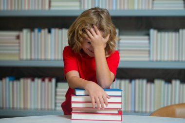 Okul çocuğu, okul kütüphanesinde gülen küçük bir öğrenci. İlkokuldan bir çocuk bir kitapçıda kitap okudu.