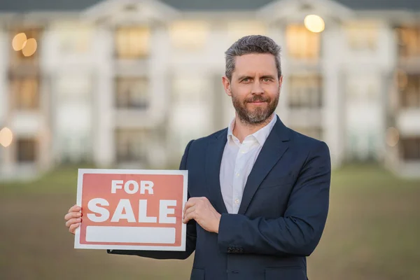 House owner, real estate agents hold sign for sale. Housing estates in the project, buying and selling housing estates. Real estate trading ideas and bank loans for buying and selling houses and land