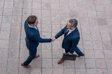 İş adamı el sıkışıyor. İki işadamı dışarıda tokalaşıyor. El sıkışın iş adamları. Takım elbiseli iki iş adamının el sıkışması. Ortaklık ve liderlik. Başarı girişimciliği