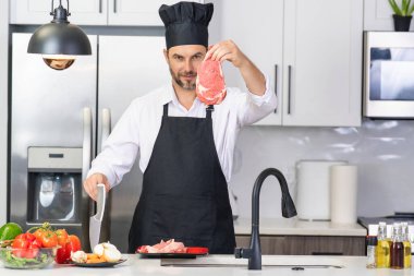 Modern mutfakta yemek pişiren çekici bir adam. Evde yemek pişiren yakışıklı adam mutfakta salata hazırlıyor. Modern mutfakta yemek hazırlayan sıradan bir adam. Olgun bir adam mutfak masasında yemek hazırlıyor.