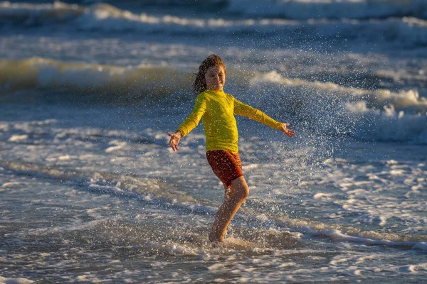 夏の日に熱帯のビーチでランニングや遊びをする子供 子供は野外活動のライフスタイルを楽しむ 海での夏休み 夕暮れ時に浜辺を走っている少年 夏休みの子供たち — ストック写真