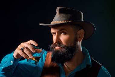 Takım elbiseli sakallı ve bıyıklı hipster, iş gününden sonra alkol içer. Neşeli sakallı adam pahalı viski içiyor