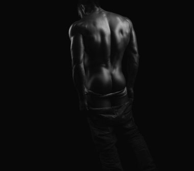 Panties down. Young mens naked ass and back on black isolated background. Metrosexual concept. Shirtless undressed sexy man turned back. Masculine buttocks