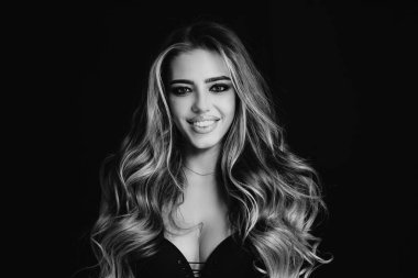 Uzun, pürüzsüz, düz saçlı güzel bir kadın. Uzun kıvırcık saçlı, sarışın bir kadın. Siyah arka planda gülümseyen güzel bir kadının güzel portresini kapat.