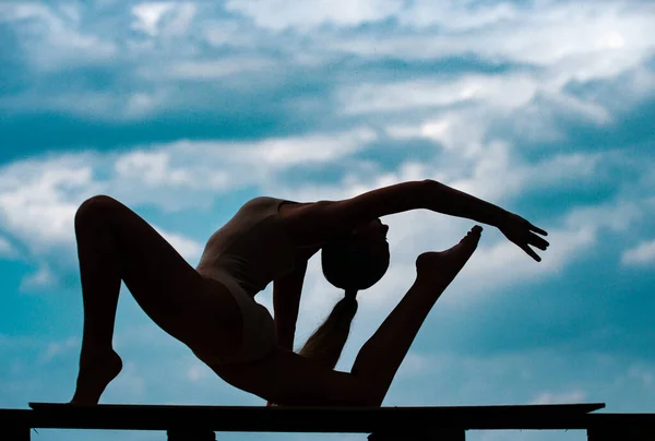 曇り空の背景に女性のフィットモデルのシルエット ストレッチとモチベーション 女性体操選手体操アクロバット — ストック写真