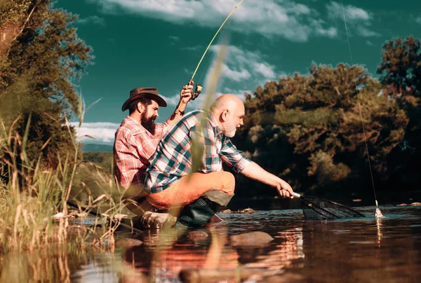 两个男人朋友在钓鱼 飞鱼垂钓者站在河水中抛掷 老少渔夫 — 图库照片