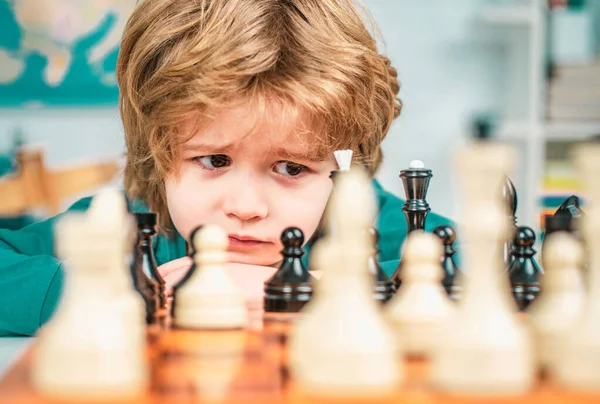 Pupil kid thinking about his next move in a game of chess. Concentrated  little boy sitting at the table and playing chess Stock Photo - Alamy