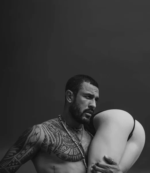 强壮的 肌肉发达的 留着胡子的男人牵着性感的女人 性感的屁股与灰色背景隔离在一起 永恒的爱与信任的概念 男人抱着性感辣妹 — 图库照片