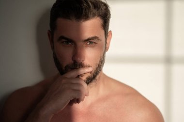Çekici bir adamın erkek yüzü kozmetik reklamındaki krem için yakın plan portresi. Çıplak omuzlar, cilt bakımı, sağlık, cilt için kozmetik. Erkek güzeli. Traş, saç şekillendirme.