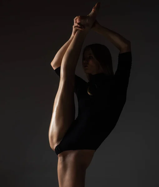 足の分割 柔軟な女の子はストレッチのための体操を行います 美しいセクシーな柔軟な女性はセクシーな柔軟な体を示しています 黒に伸縮する柔軟性 強い柔軟性の女性の体 — ストック写真