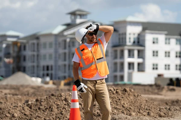 累了的工人 建筑工人戴着硬礼帽在工地进行建筑工程 建筑工地附近一名戴头盔的建筑工人 工作的缔造者 — 图库照片