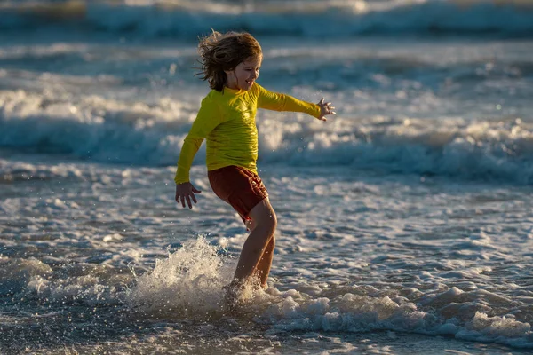 気をつけて海を走ってる子供 暖かい夏の日に海の近くを走る幸せなかわいい子供 かわいい子供の男の子が走り 家族の休暇に海や海で飛び散っています ビーチを走っている子供は — ストック写真
