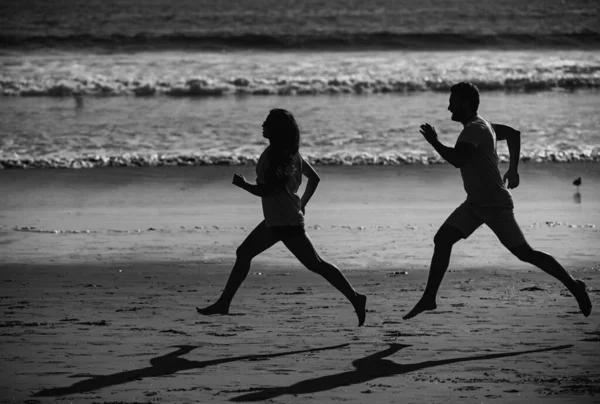 若い男と女が海に沿ってジョギングを実行しています ビーチを走るカップル — ストック写真