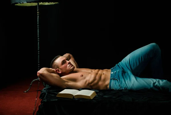 男はベッドで裸で本を読んでリラックスします ラグジュアリーな雰囲気 セックスとリラクゼーションの概念 — ストック写真