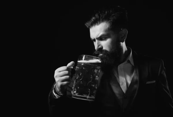 穿着经典西装的复古男人喝啤酒 留胡子的家伙对黑色背景的高杯啤酒很满意 — 图库照片