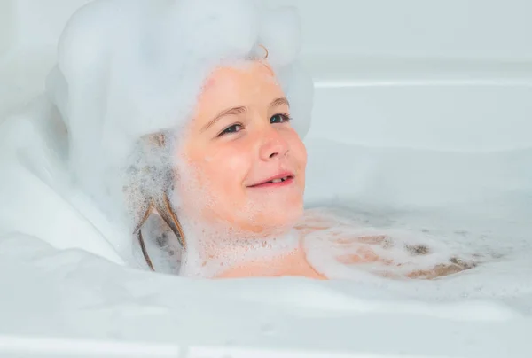 孩子们洗发水洗澡时带着泡泡的小男孩 可爱的孩子洗澡了 躺在一个用肥皂和洗发水泡的白色浴缸里 — 图库照片