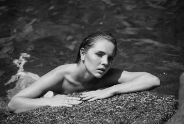 Okyanusta ya da deniz suyunda yüzen güzel genç bir kadın. Rahatlıyor ve kendine bakıyor. Lüks tatil köyünde yaz elbisesi içinde zarif bir kızın moda portresi.