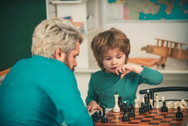 Mutlu bir aile. Öğretmen ve okul çocuğu sınıfta satranç oynuyorlar. Çocuk erken gelişimi