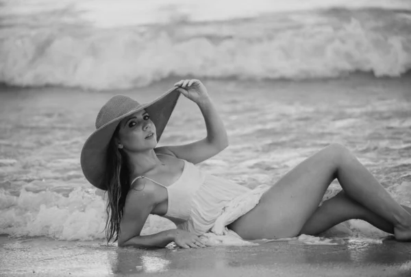 ビーチで日光浴を楽しむわら帽子の美しい女の子 若い日焼けした女性は海辺で風を楽しんでいます 背景に海と笑顔ケアフリー女性 — ストック写真