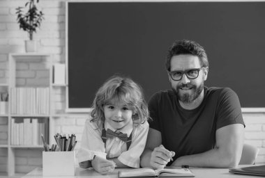 Pupil kid student and teacher tutor in classroom at school lesson. Elementary school boy in classroom on lesson. Teacher explaining to pupil