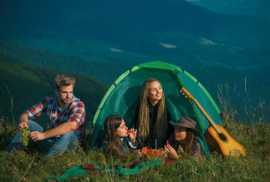 Kampta karpuz yiyen bir grup mutlu arkadaş. Kamp arkadaşlığı konuşuyor.