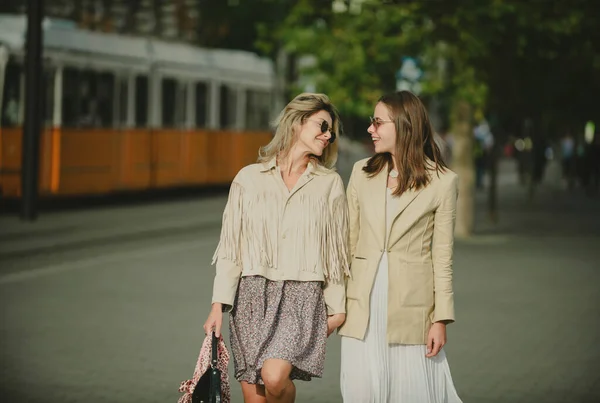 两个发射的年轻女子戴着太阳镜在城市里行走 有趣的假期浪漫的旅行城市生活方式 — 图库照片