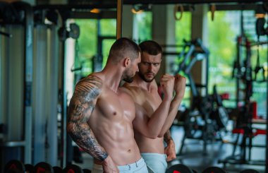 Muscular man workout in the gym. Athletic man having weight training in gym. Handsome man with strong muscles workout in the gym. Portrait of sexy muscular male with dumbbells. Bodybuilder exercise