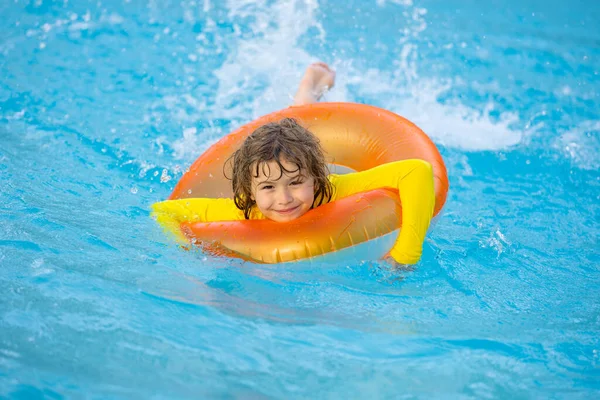 Kid playing with inflatable ring in swimming pool on hot summer day. Kid with inflatable ring in swimming pool. Summer vacation. Summer holiday. Summertime kids weekend