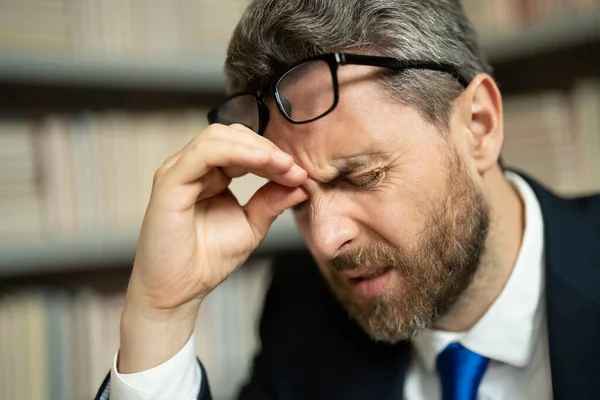 Close up face of stressed man with headache migraine. Businessman in office having headache. Business man in suit work on laptop at home office take off glasses suffer from migraine or headache
