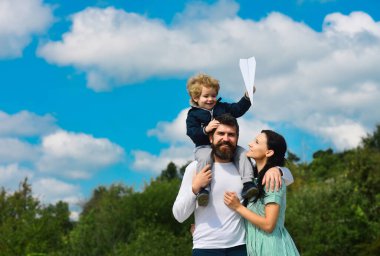 Mutlu aile, anne, baba ve çocuk, gülüyor ve oyuncak kağıt uçakla eğleniyorlar. Oyuncak uçakla oynayan ve geleceği hayal eden çocuk, konsept hayaller ve seyahatler. Çocuk günü, rüya görme özgürlüğü