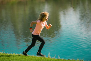 Çocuk koşucular parkta koşar. Sportif genç çocuk dışarıda koşuyor ve antrenman yapıyor.